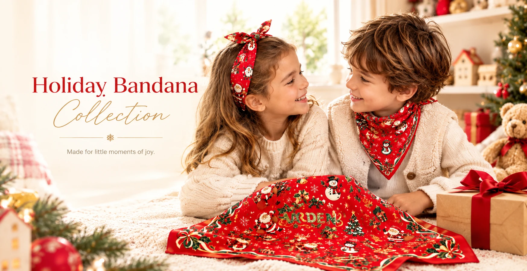 Two children in a bright holiday living room, a girl tying on a red Santa-print headband while a boy wears a matching red bandana as a neckerchief, beside an ARDEN Christmas bandana laid flat, wrapped gifts and a decorated tree